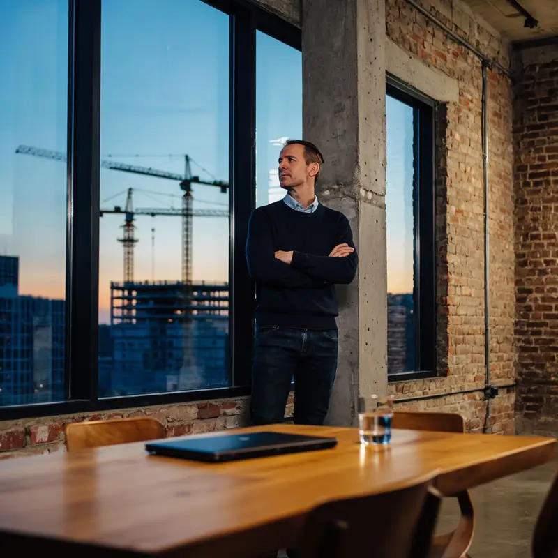 A reflective founder looks over the city, considering long-term strength over rapid expansion.